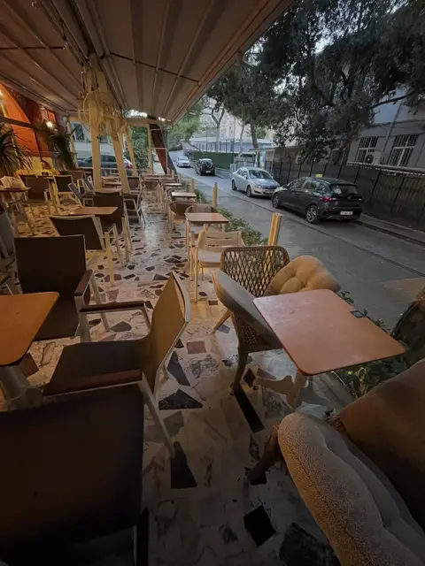Kafe terasında sandalyeler ve minderli hasır koltuklar — Bornova, İzmir