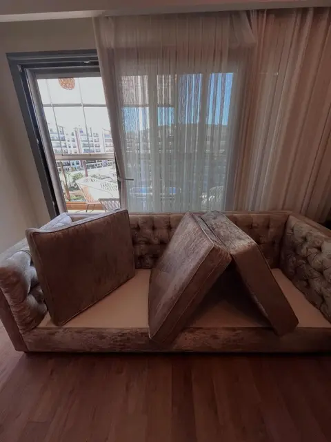 Bej kadife kapitoneli kanepe, minderleri kurumaya bırakılmış — İzmir